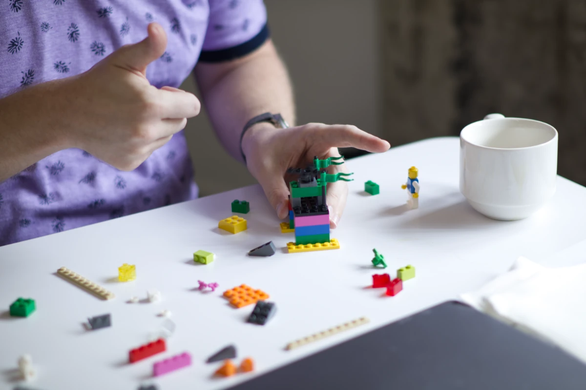 A participant giving a thumbs-up beside a colorful LEGO model